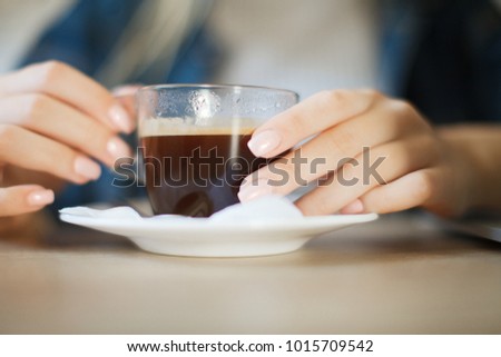 Girl drinking coffee in a coffee shop. Girl drinking an Americano at the bar. A mug of coffee. Americano in glass mug. Coffee break
