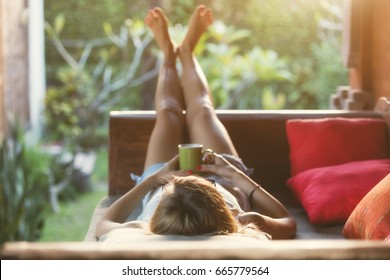 Girl drinking coffee / tea and enjoying the sunrise / sunset in garden. Shallow focus on the head / hair.