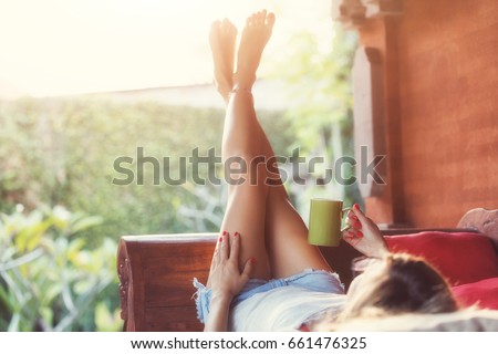 Girl drinking coffee / tea and enjoying the sunrise / sunset in garden.