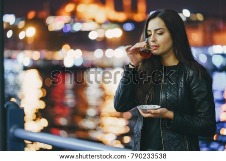 girl drinking hot tea by the bosphorus in Istanbul Turkey