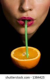 Girl drinking an orange from a straw.