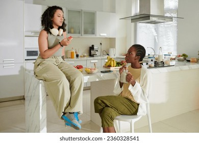 Girl drinking smoothie and looking at friend eating watermelon and telling news - Powered by Shutterstock