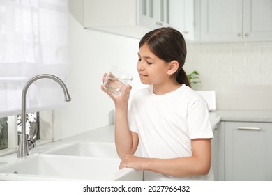 Girl Drinking Tap Water From Glass In Kitchen