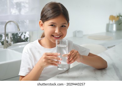 Girl Drinking Tap Water From Glass In Kitchen