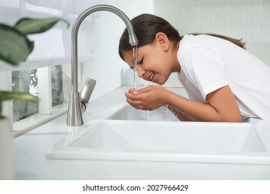 Girl Drinking Tap Water Over Sink In Kitchen