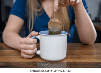 Girl drinking tea for digestion and weight loss while sitting at a wooden kitchen counter - Powered by Shutterstock