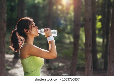 Girl Drinking Water From Bottle In Forrest