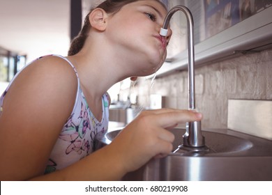 Girl Drinking Water From Faucet At School