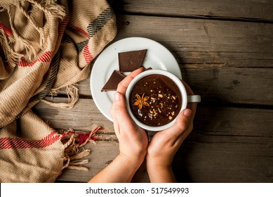 Girl drinks hot chocolate mug, with christmas present on rustic table with blanket or plaid from above, cozy and tasty breakfast or snack. Hands in picture, top view - Powered by Shutterstock