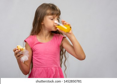 A girl drinks orange juice and eats a bun - Powered by Shutterstock