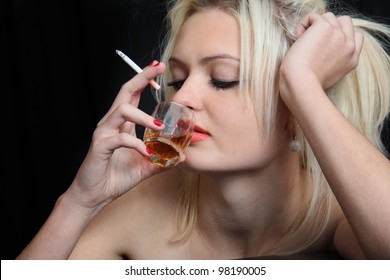 girl drinks whisky, smokes  cigarette.  black background