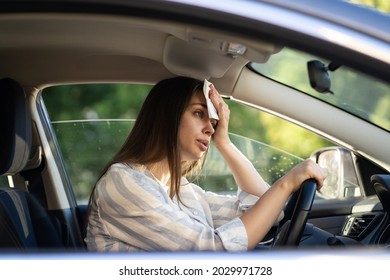Girl driver being hot during heat wave in car, suffering from hot weather, has problem with a non-working air conditioner, wipes sweat from her face with tissue. Summer, heat concept. 
