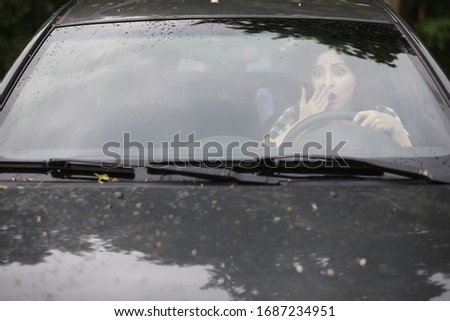 Similar – Eine Frau in einer mit großem Ausschnitt sitzt in ihrem Auto auf der rechten Seite vorne und schminkt sich, legt Schmuck an. Man kann sie durch die Reflexion in der Windschutzscheibe nicht erkennen