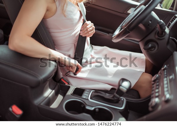 girl driving car, in summer in city, fastens\
her seat belt, latches lock. View of interior of car close-up\
steering wheel. Girl in a dress, automatic transmission, armrest\
and cup holders background