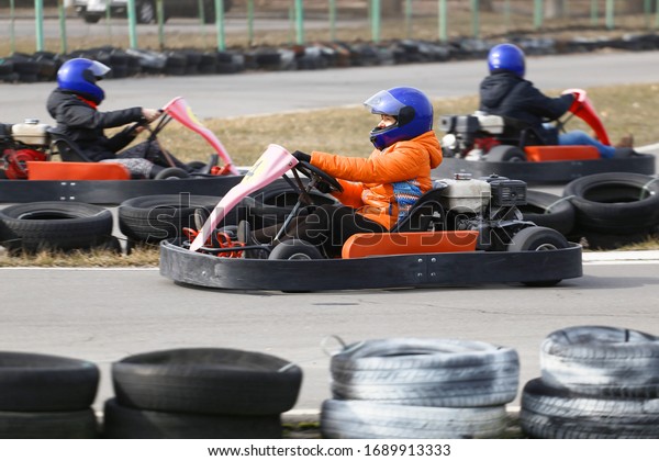 girl is driving Go-kart car with speed in a\
playground racing track.