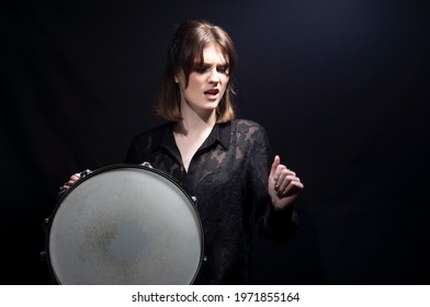 Girl With Drum Portrait Of A Smiling Young Beautiful Drummer Girl, In Black, Holding A Snare Drum, Posing. On A Black Background