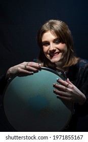 Girl With Drum Portrait Of A Smiling Young Beautiful Drummer Girl, In Black, Holding A Snare Drum, Posing. On A Black Background