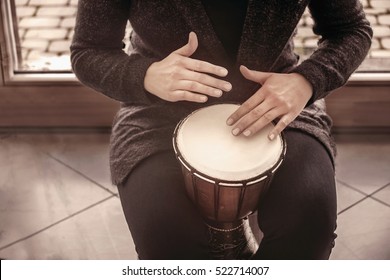 Girl drummers hands playing percussion bongo in a house