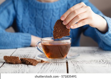 Girl Dunk Biscuits In Tea Cup On Table