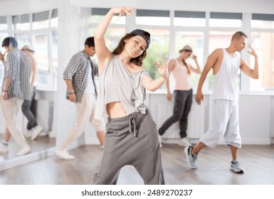 Girl during hip hop dance rehearsal, left general group of dancers, poses, performs broken movements, demonstrates mastery of modern dance. - Powered by Shutterstock