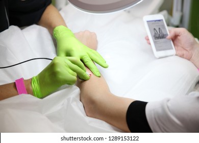 Girl during the procedure to remove unwanted hair on his hand looking at your phone