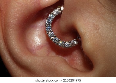 Girl ear piercing. Macro.
				Daith piercing + cubic zirconia clicker.