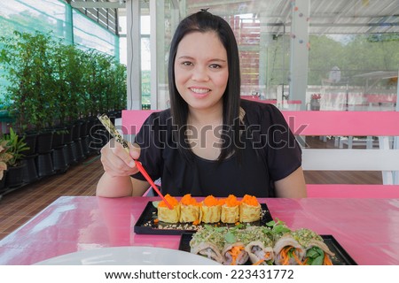 Girl eat sushi egg and bacon chili sauce in restaurant