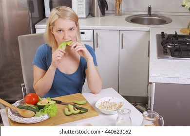 Girl Eating An Avocado And Salad, Healthy Eating, Diet. Pensive Woman Looks At The Tomato. In The Kitchen. Bright Room