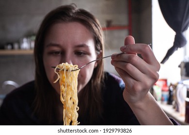 girl eating a fork instant noodles with seasonings and spices, student food