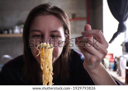 girl eating a fork instant noodles with seasonings and spices, student food