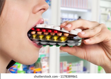 Girl eating lots of pills on background