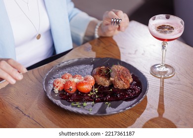 Girl Eating Meat Medallion With Tomatoes Close-up In A Modern Restaurant