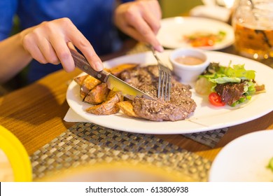 Girl eating meat with salad in a restaurant