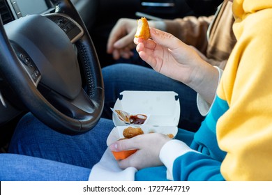 Girl Eating Nuggets Sitting At The Wheel Of A Car. Fast Food, Takeaway, Snacks On The Road.