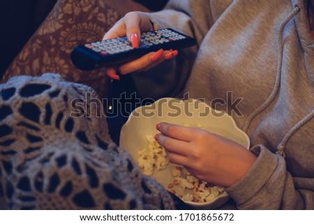 Girl is eating popcorn while watching TV