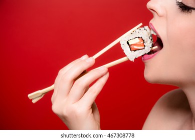 A girl eating a sushi roll.