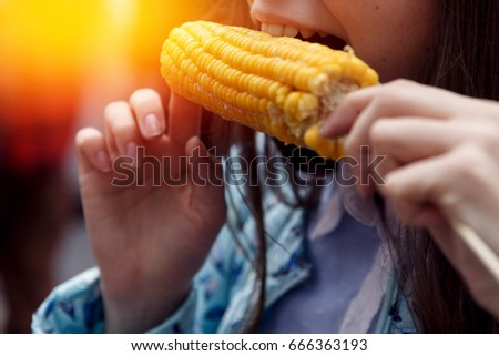 girl is eating yellow boiled corn outdoors. Smile close-up. The concept is useful food on the street