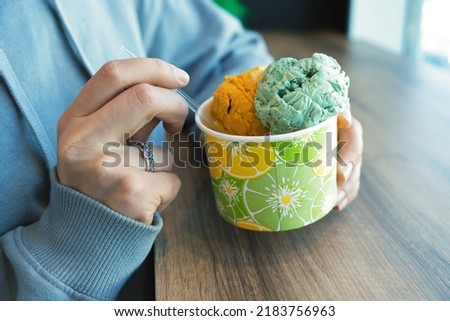 a girl eats balls of pistachio ice cream in a cafe