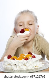Girl eats a cake on white background.