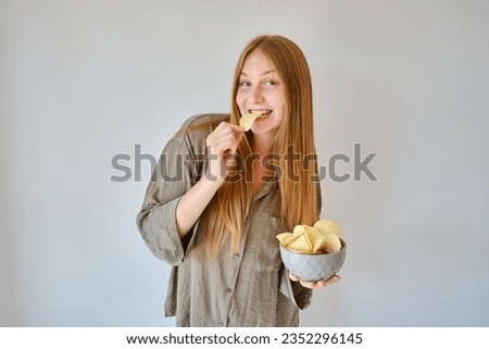 A girl eats crispy potato chips from a bowl on the couch. Quick snack. Calories and diet