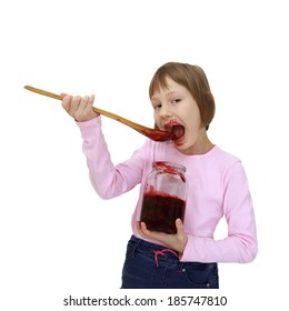 Girl eats jam from jar using a big wooden spoon isolated on white background