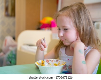 the girl eats with a spoon from a plate sitting at the table - Shutterstock ID 1706671126