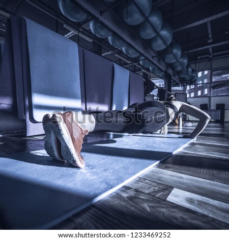 The girl is engaged in fitness in the gym. Toned image. concept of a healthy lifestyle and exercise in the gym. The girl doing female push-ups and plank during training from the back close up