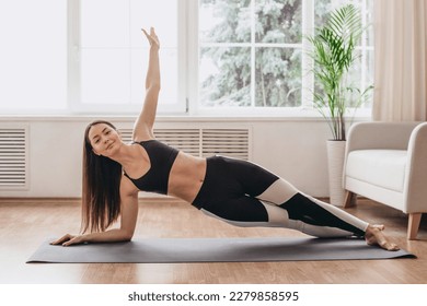 The girl is engaged in fitness at home. Yoga, Pilates, stretching, exercises for a beautiful body. Side plank. Healthy lifestyle - Powered by Shutterstock