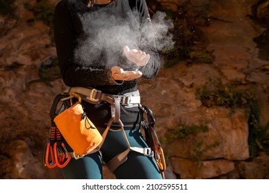 The girl is engaged in rock climbing, uses white powder of magnesia, claps her hands close-up, the woman leads an active lifestyle, climbs the mountains outdoor.