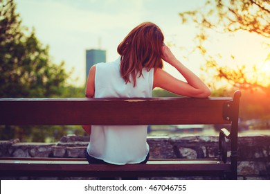 Girl enjoying city view from a bench in sunset / sunrise time.
