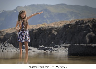 girl enjoying the good weather in natural pools on the beach and watching the seagulls flying around her
