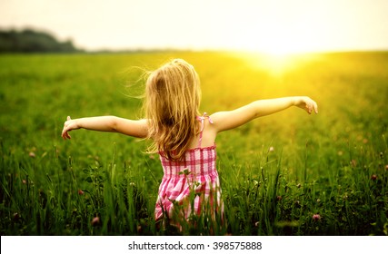Girl enjoying nature in meadow. Outstretched arms fresh morning air summer field at sunrise