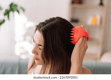 Girl enjoys doing herself a head massage using a scalp massager.