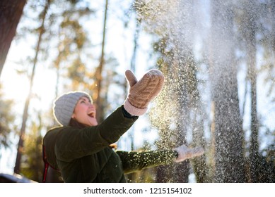Girl enjoys winter, frosty day, snow. playing with snow, a woman throws white, loose snow into the air. Walk with winter forest.